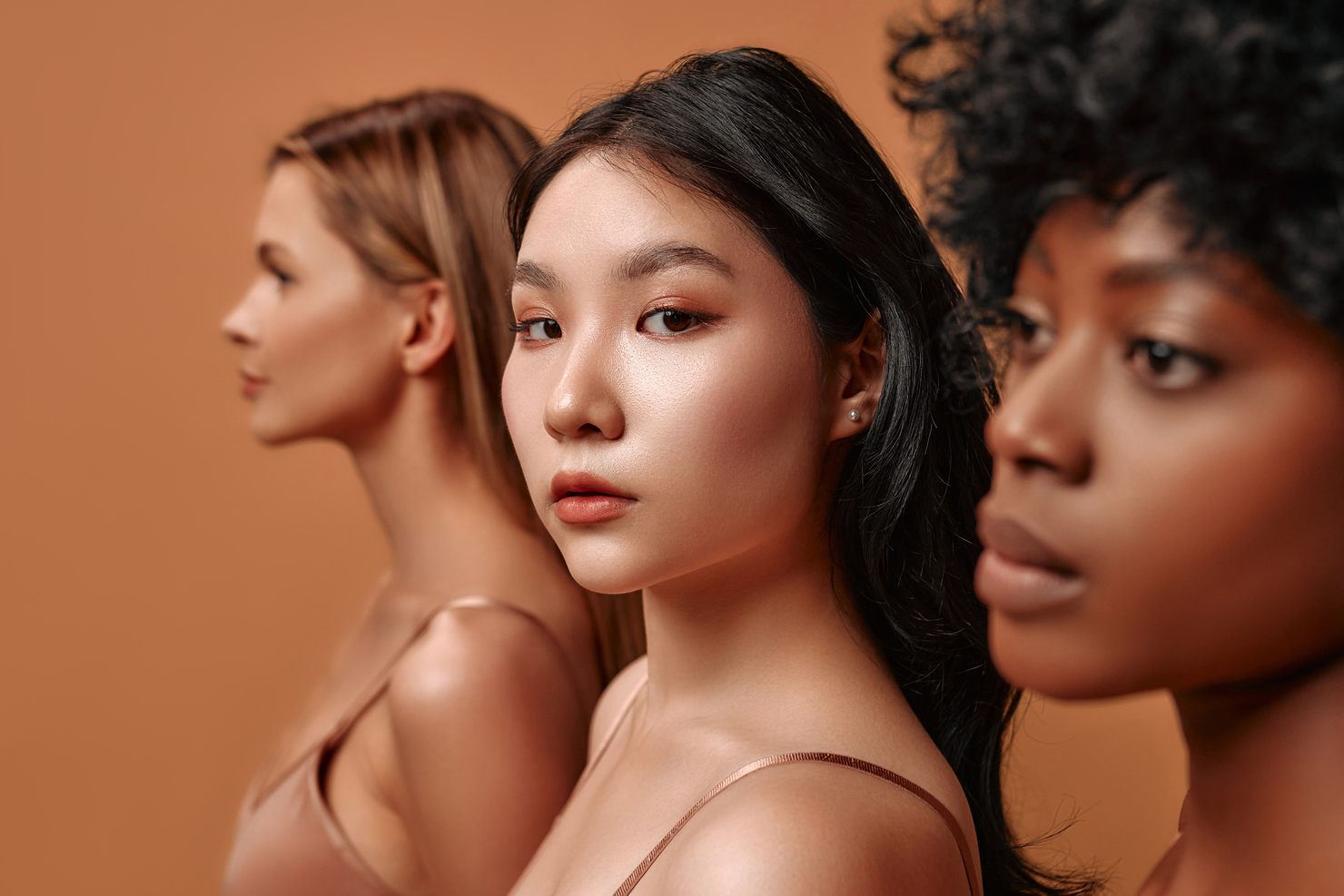 Three women, close-up on one looking to the camera, representing Adelia Skincare's natural beauty brand